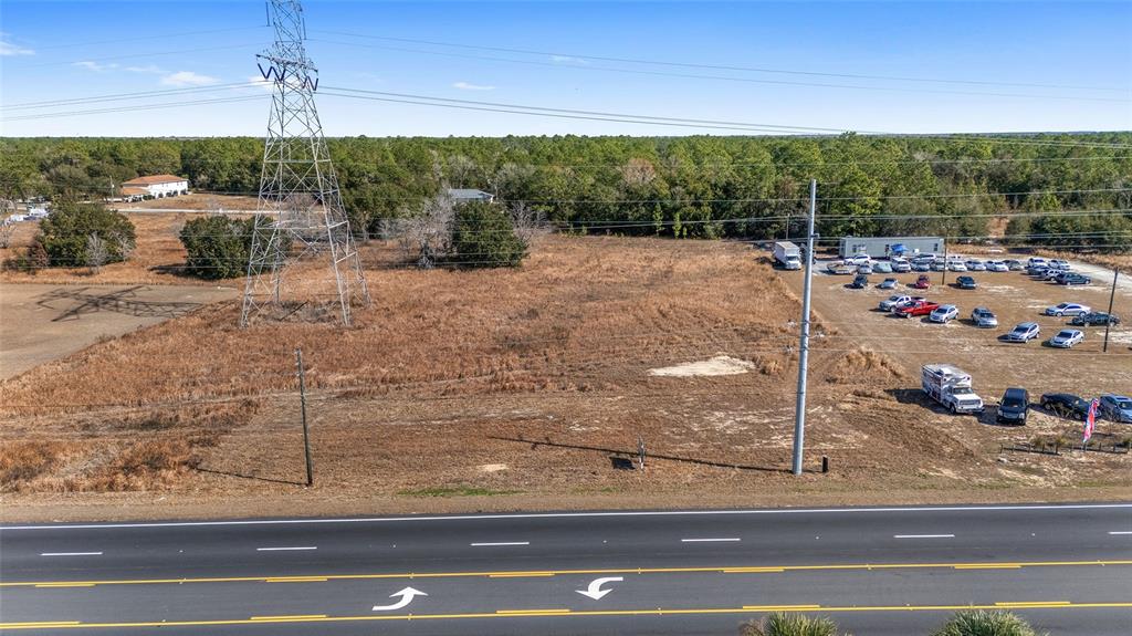 An aerial view shows a vacant, grassy lot situated next to a car dealership — LOT 15 & 16 SE MARICAMP ROAD, OCALA, FL