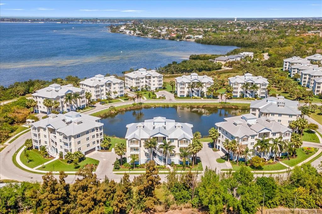 An aerial view shows a residential complex with multiple buildings surrounding a central pond — 3418 79TH STREET CIRCLE W UNIT 303, BRADENTON, FL