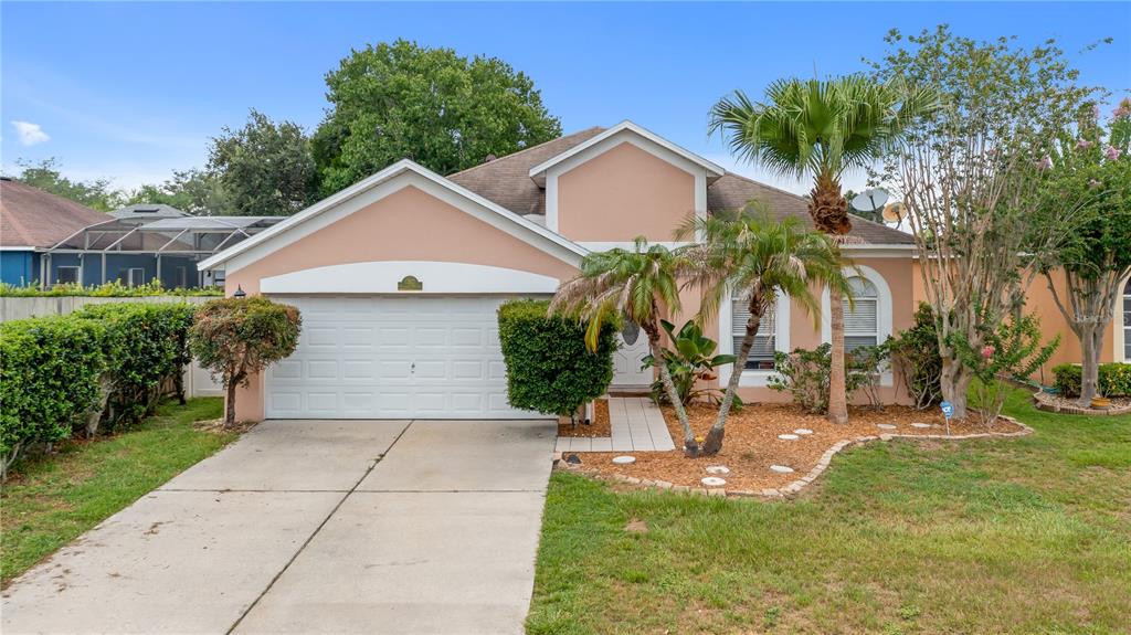 A single-story house with a peach-colored exterior, a two-car garage, and a palm tree — 12827 WOODBURY GLEN DRIVE, ORLANDO, FL