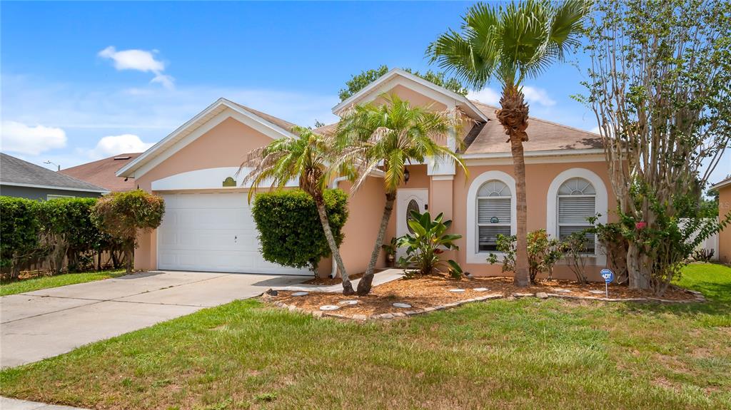 A single-story house with a peach-colored exterior, a two-car garage, and two palm trees — 12827 WOODBURY GLEN DRIVE, ORLANDO, FL