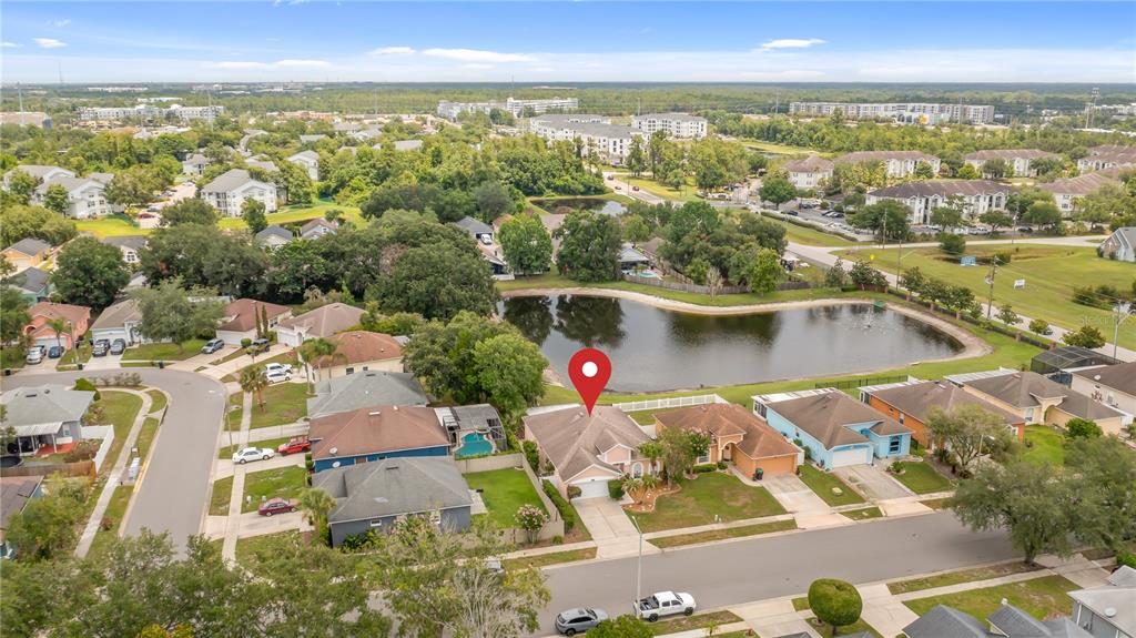 An aerial view shows a suburban house with a red pin located near a pond — 12827 WOODBURY GLEN DRIVE, ORLANDO, FL
