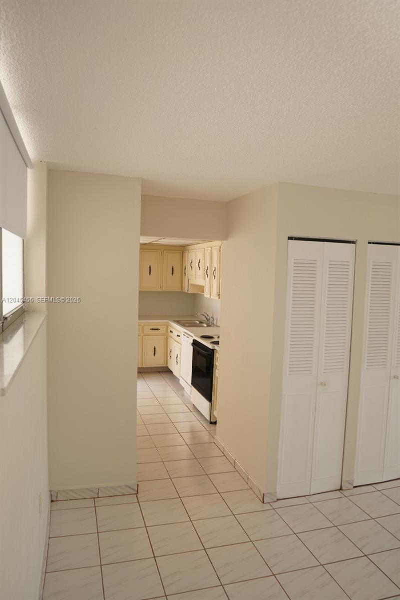 A view from a tiled room looking into a kitchen with light-colored cabinets — 1750 James Ave # 7K, Miami Beach FL 33139, MIAMI BEACH, FL