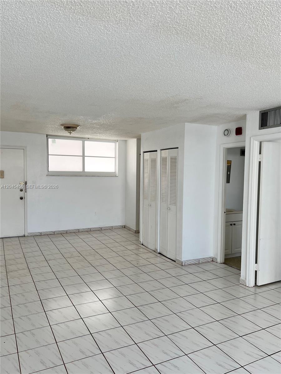 A room with white tiled floors, a window, and two sets of louvered closet doors — 1750 James Ave # 7K, Miami Beach FL 33139, MIAMI BEACH, FL