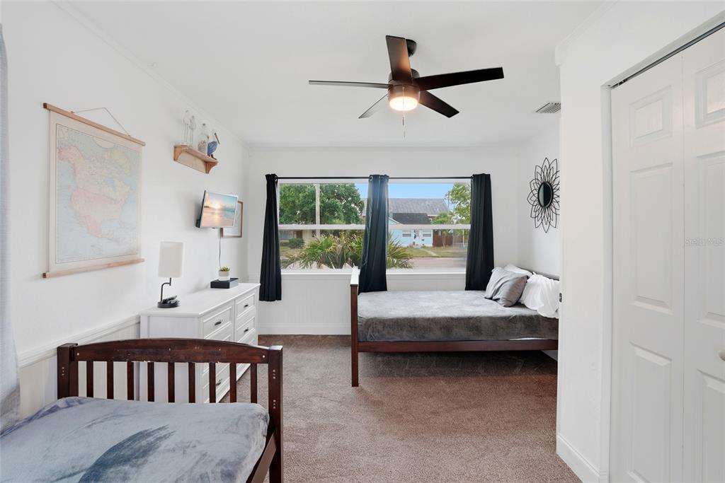 A bedroom features two beds, a white dresser, a ceiling fan, and a large window — 4627 1ST AVENUE N, ST PETERSBURG, FL