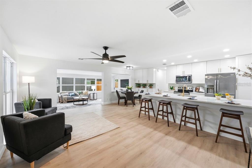 An open-concept kitchen and living area with white cabinets, a large island, and wood flooring — 6324 CASE AVENUE, BRADENTON, FL