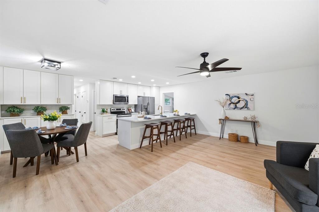 A bright, open-concept kitchen and dining area features white cabinetry, a central island, and flooring — 6324 CASE AVENUE, BRADENTON, FL