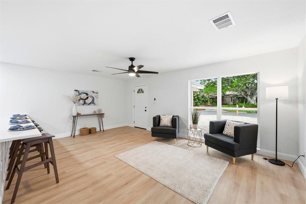 A living room with light wood floors, two dark armchairs, and a breakfast bar — 6324 CASE AVENUE, BRADENTON, FL