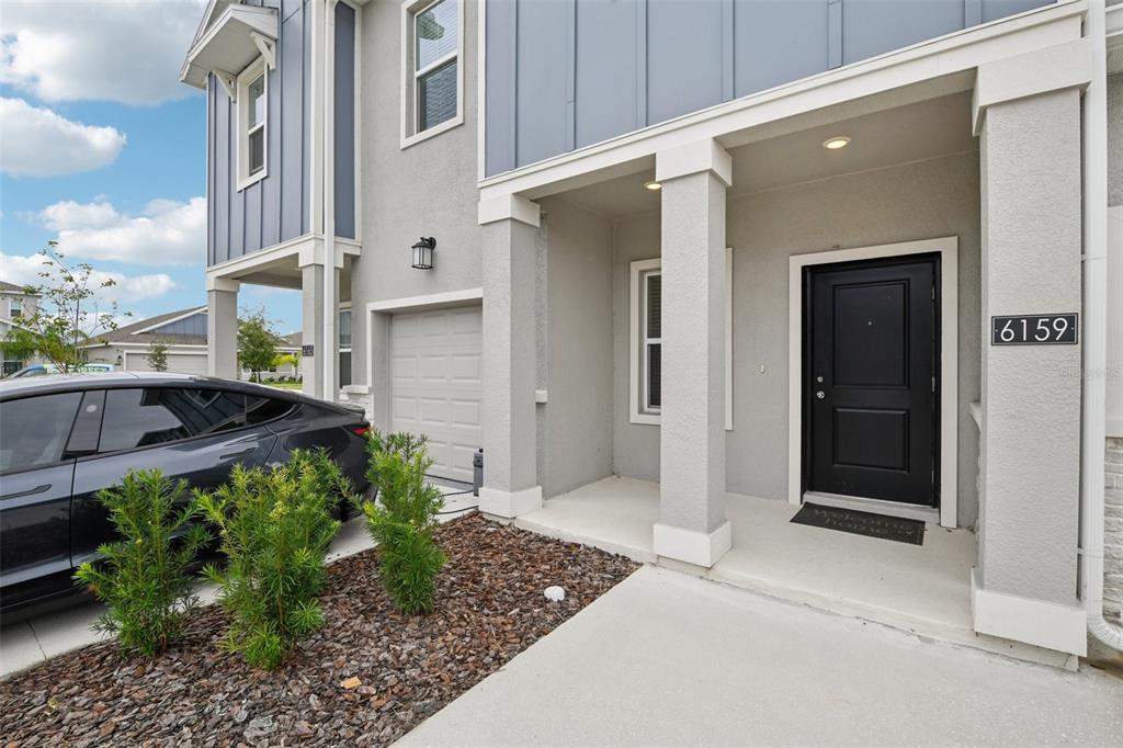 A gray two-story house exterior features a covered porch, a black front door, and a garage — 6159 PEACEFUL PARK WAY, CLERMONT, FL