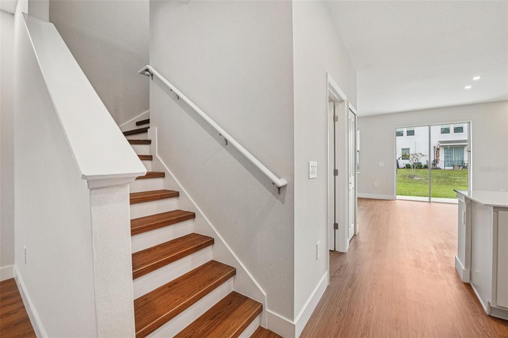 A staircase with wooden treads and a white railing leads to an upper level — 6159 PEACEFUL PARK WAY, CLERMONT, FL