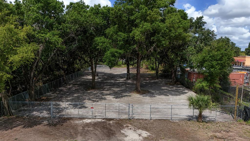 A fenced, gravel-covered vacant lot features several large trees and a small palm tree — 208 S FRANKLIN STREET, PLANT CITY, FL