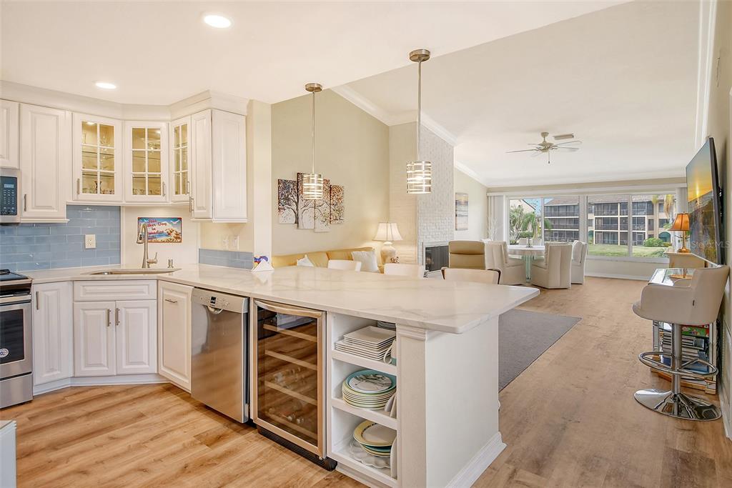 A kitchen with white cabinets and a marble island overlooks an open-concept living and dining area — 5644 ASHTON LAKE DRIVE UNIT 5644, SARASOTA, FL