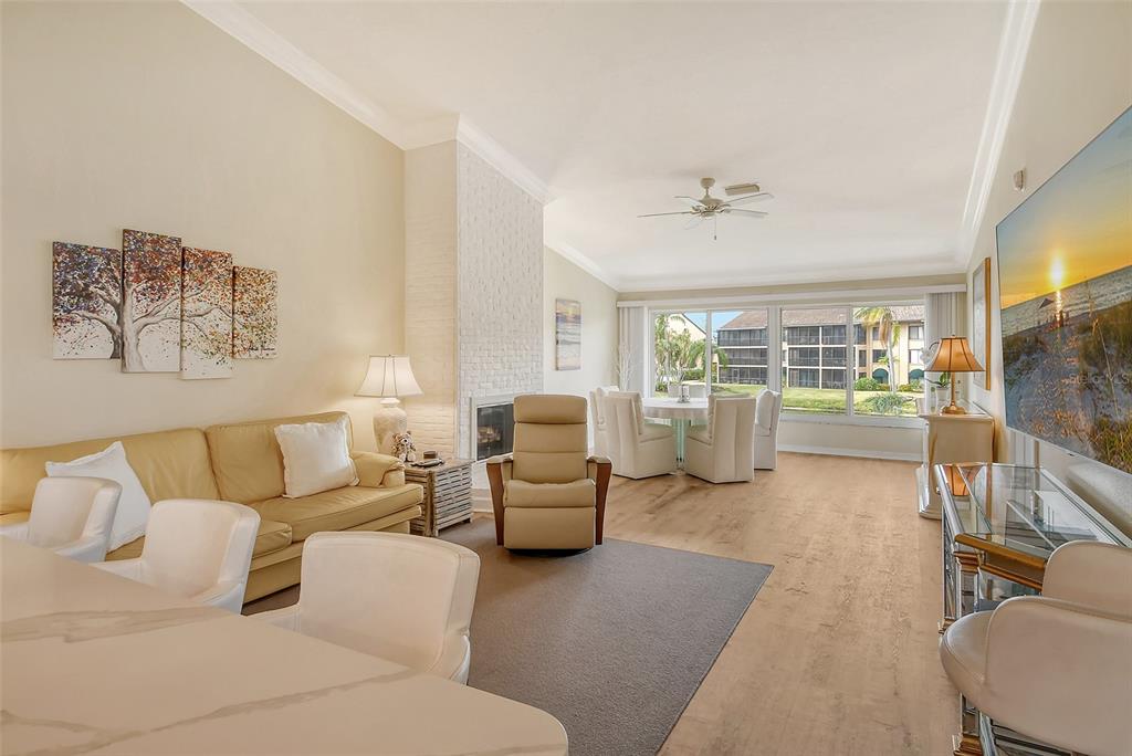 A living room with a beige sofa, recliner, fireplace, and dining area overlooking a building exterior — 5644 ASHTON LAKE DRIVE UNIT 5644, SARASOTA, FL