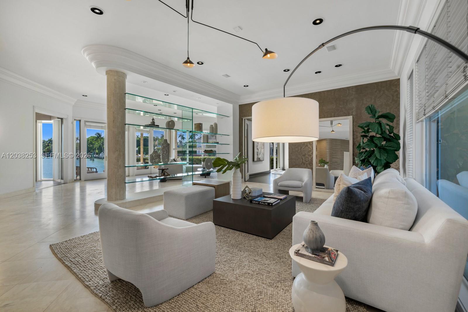 A modern living room features a stone pillar, glass shelving, and a view of water — 6500 N Bay Rd, Miami Beach FL 33141, MIAMI BEACH, FL