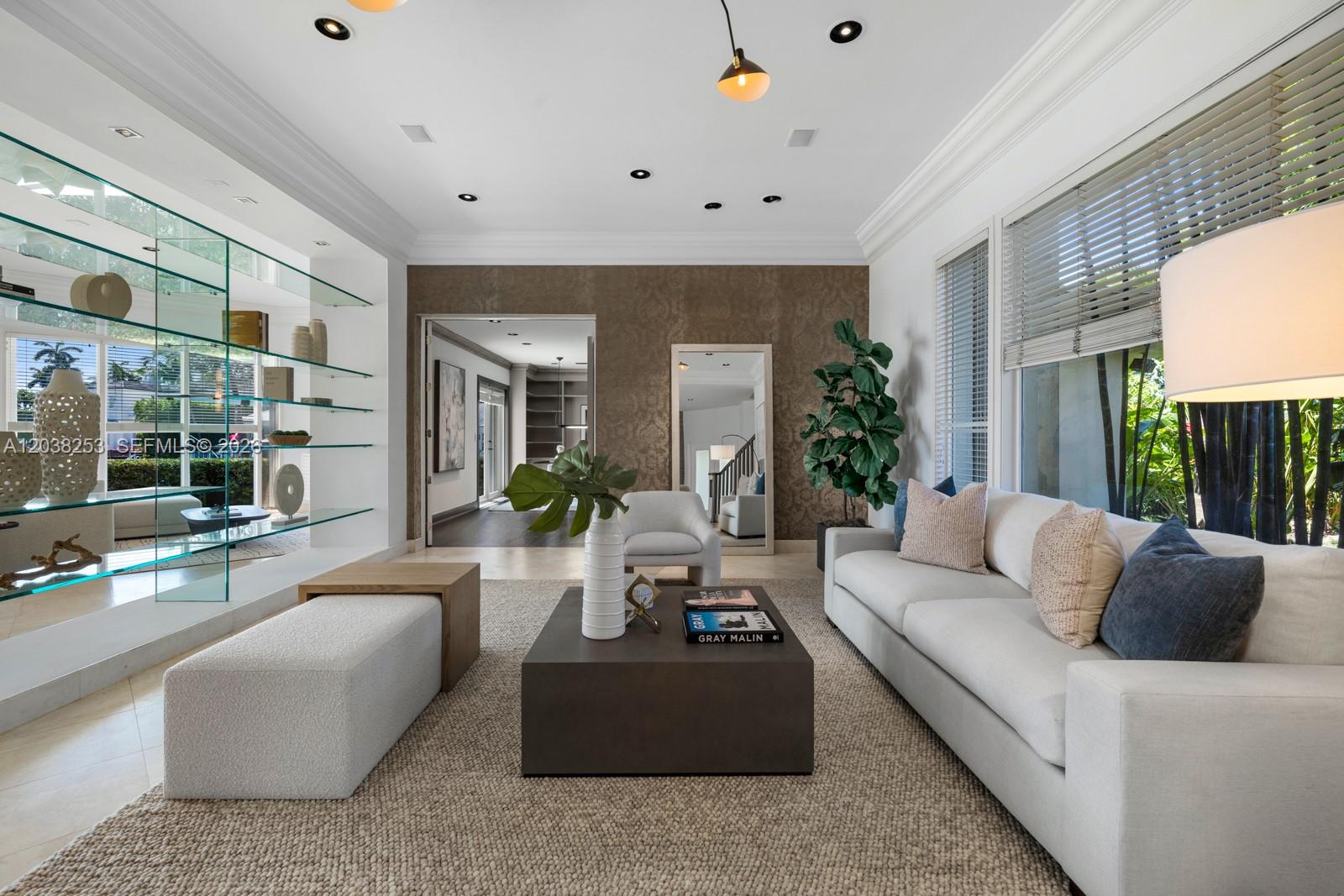 A living room features a white sofa, a dark coffee table, and glass shelving units — 6500 N Bay Rd, Miami Beach FL 33141, MIAMI BEACH, FL