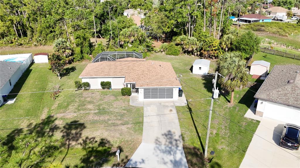 An aerial view shows a house with a brown shingled roof and a screened-in pool — 1091 LUAU STREET, NORTH PORT, FL