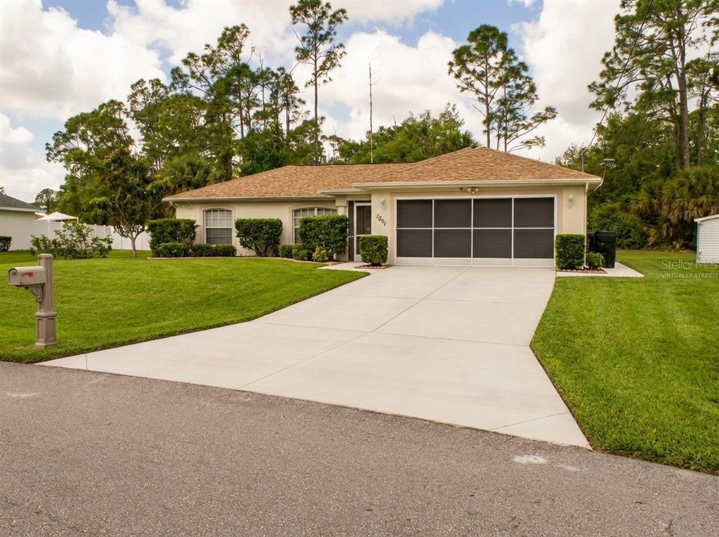 A single-story house with a tan exterior, a shingled roof, and a concrete driveway — 1091 LUAU STREET, NORTH PORT, FL