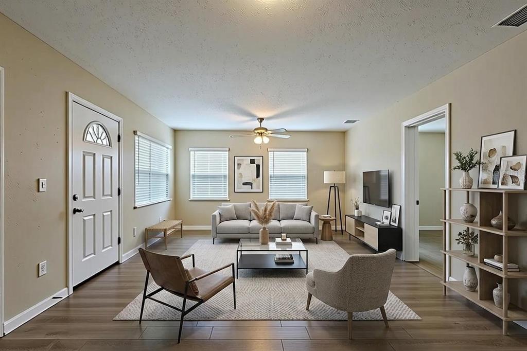 A living room features light wood-look flooring, a grey sofa, two accent chairs, and windows — 3408 PHILLIPS STREET, TAMPA, FL