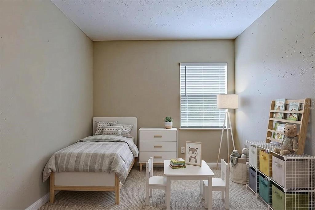 A bedroom with a twin bed, white dresser, small table with chairs, and toy storage — 3408 PHILLIPS STREET, TAMPA, FL