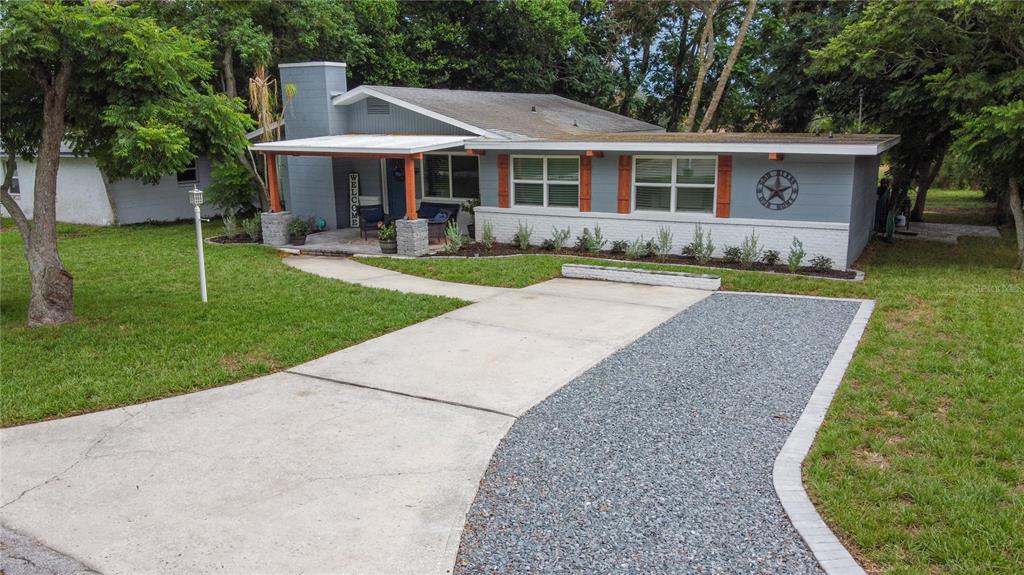 A single-story house with a gray exterior, a covered porch, and a gravel driveway — 1022 S TOWER LANE, LAKE WALES, FL