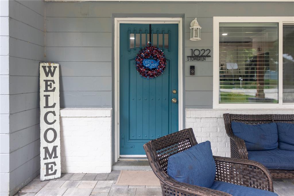 A front porch features a teal door, a welcome sign, and wicker furniture — 1022 S TOWER LANE, LAKE WALES, FL