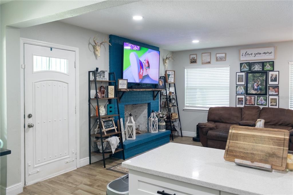 A living room features a blue painted brick fireplace, a mounted television, and a brown sofa — 1022 S TOWER LANE, LAKE WALES, FL