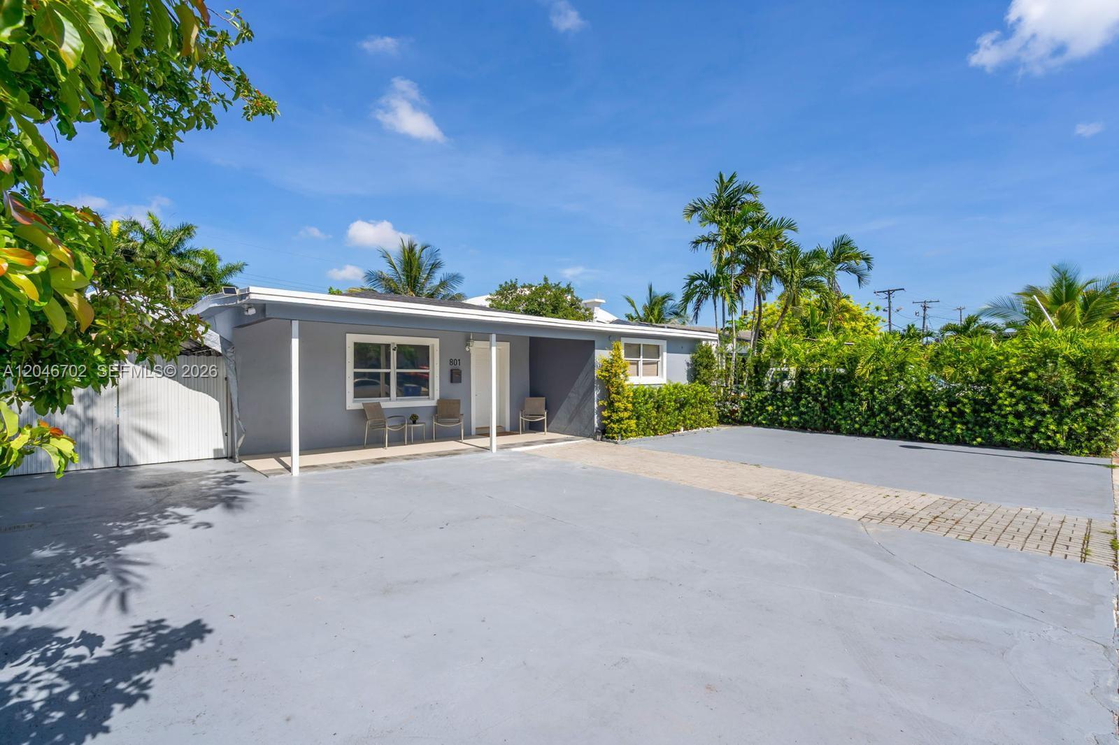 A gray single-story house features a covered front porch and a large paved driveway — 801 NW 17th Ct, Miami FL 33125, MIAMI, FL