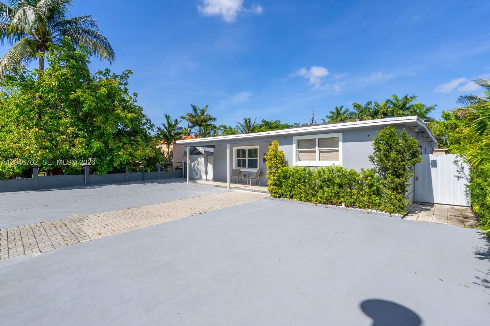 A single-story gray house features a paved driveway, a small covered porch, and landscaping — 801 NW 17th Ct, Miami FL 33125, MIAMI, FL