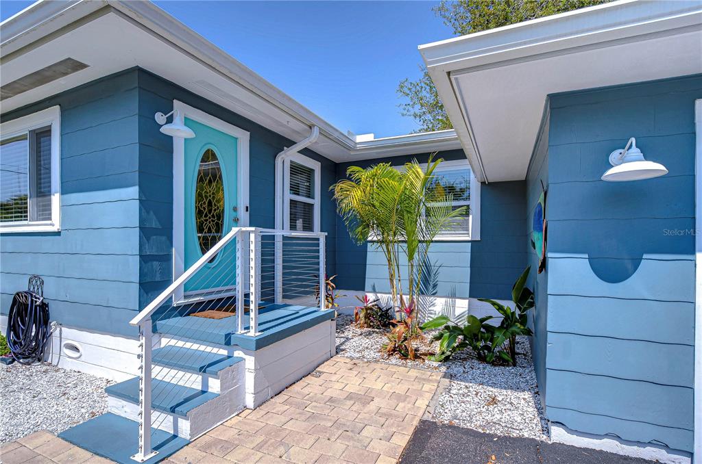 The exterior of a blue house features a turquoise front door and a stone walkway — 1922 55TH STREET S, GULFPORT, FL