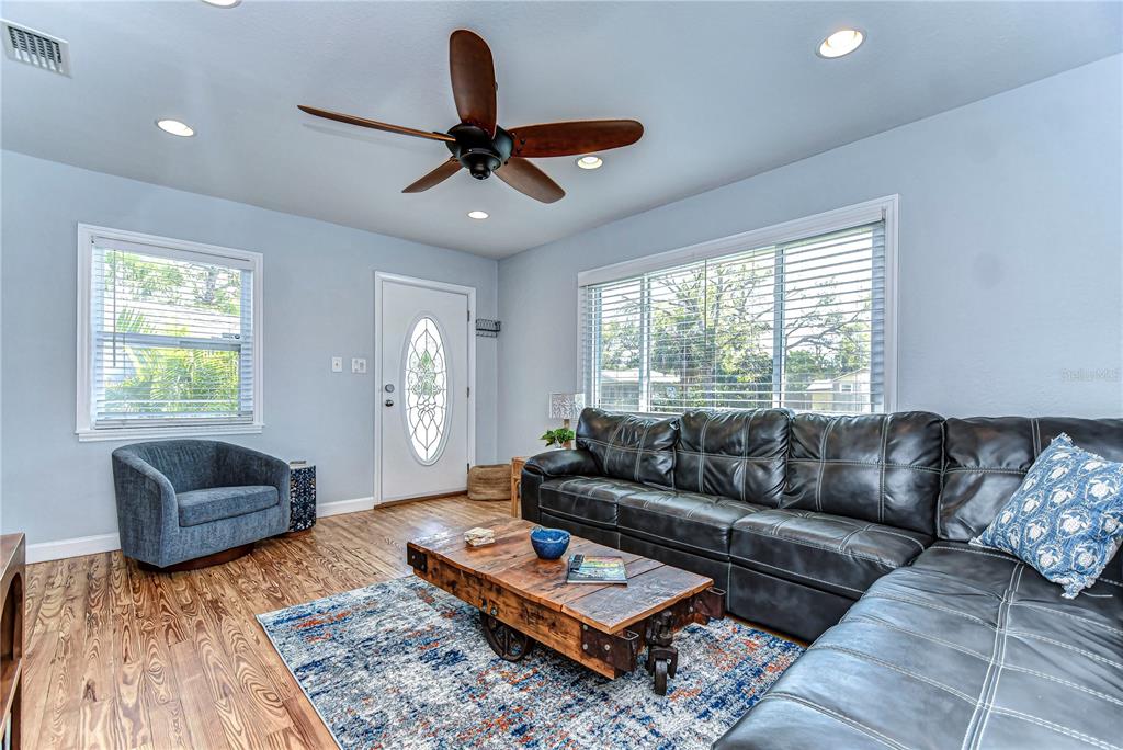 A living room features a dark leather sectional, a wooden coffee table, and a ceiling fan — 1922 55TH STREET S, GULFPORT, FL