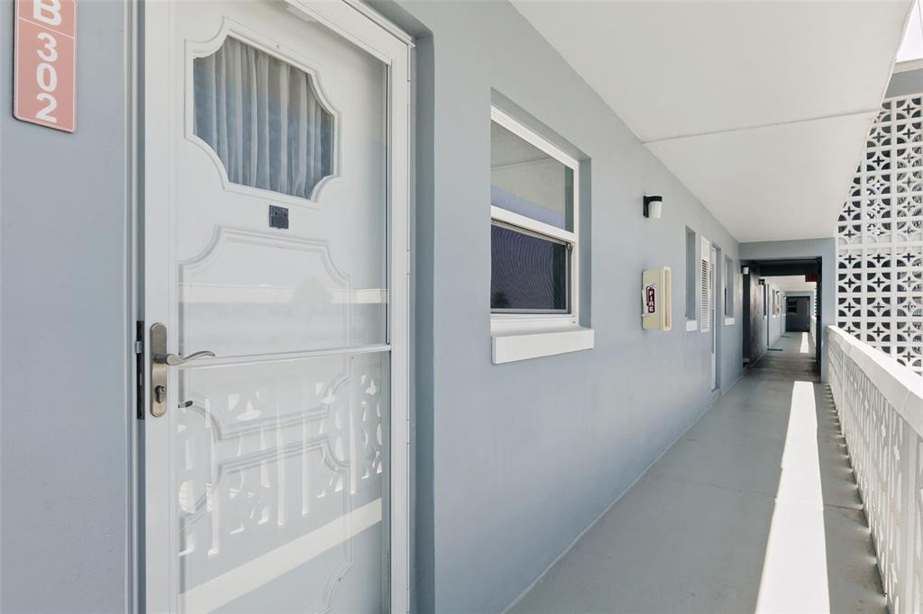 An exterior walkway leads to a white door labeled B302 at a multi-unit building — 315 N CAUSEWAY UNIT B302, NEW SMYRNA BEACH, FL