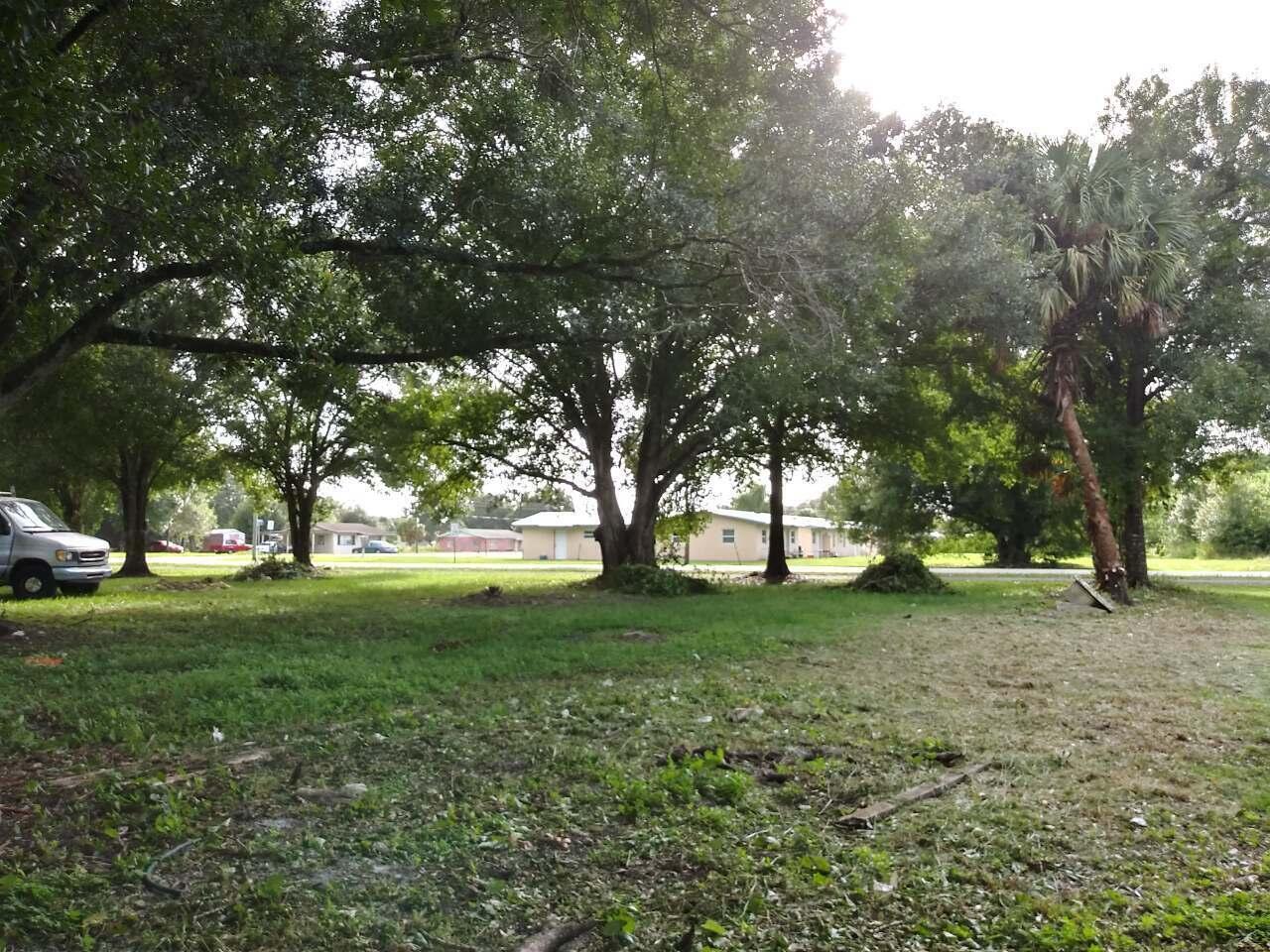 A grassy yard with several large trees and a palm tree in front of houses — 810 NW 10th Street, Okeechobee FL 34972, OKEECHOBEE, FL