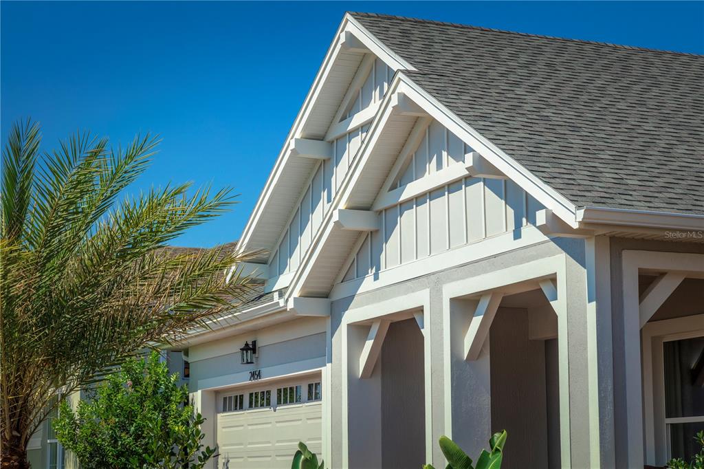 A low-angle view of a house exterior featuring a gabled roof, white trim, and siding — 2454 DREAM HOME COURT, ST CLOUD, FL