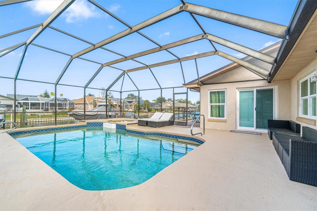 A screened-in pool patio features a swimming pool, hot tub, and outdoor lounge furniture — 5 CHEYENNE COURT, PALM COAST, FL