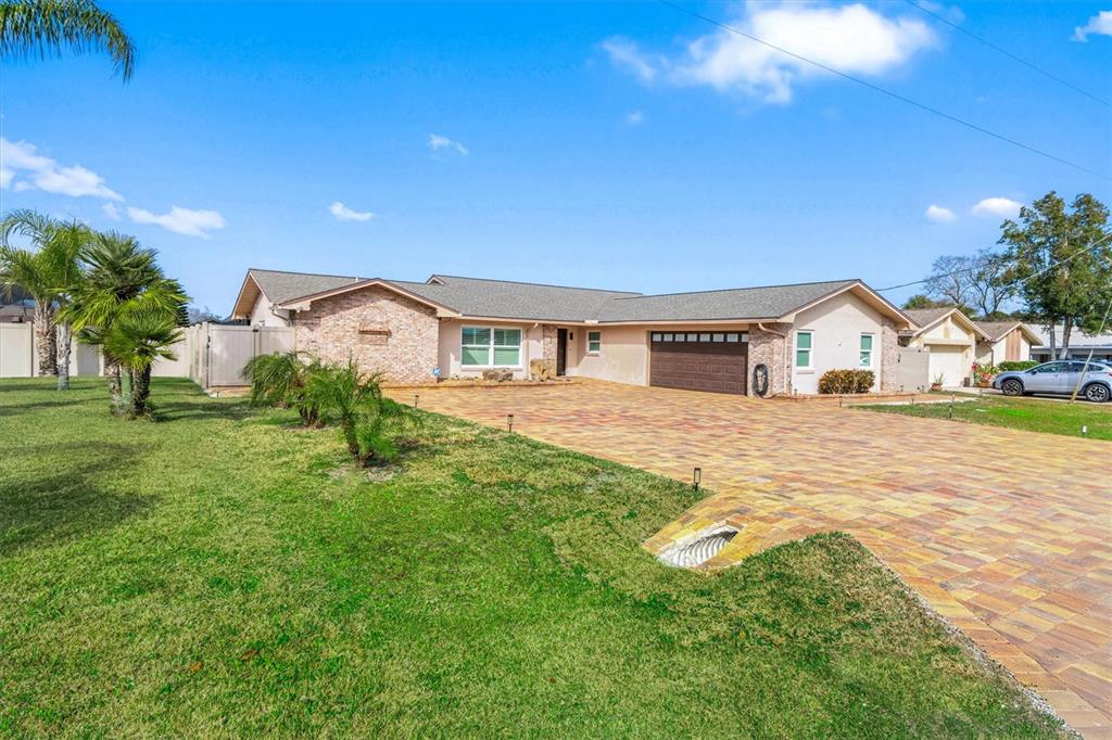 A single-story house features a brick facade, a large paver driveway, and a two-car garage — 5 CHEYENNE COURT, PALM COAST, FL