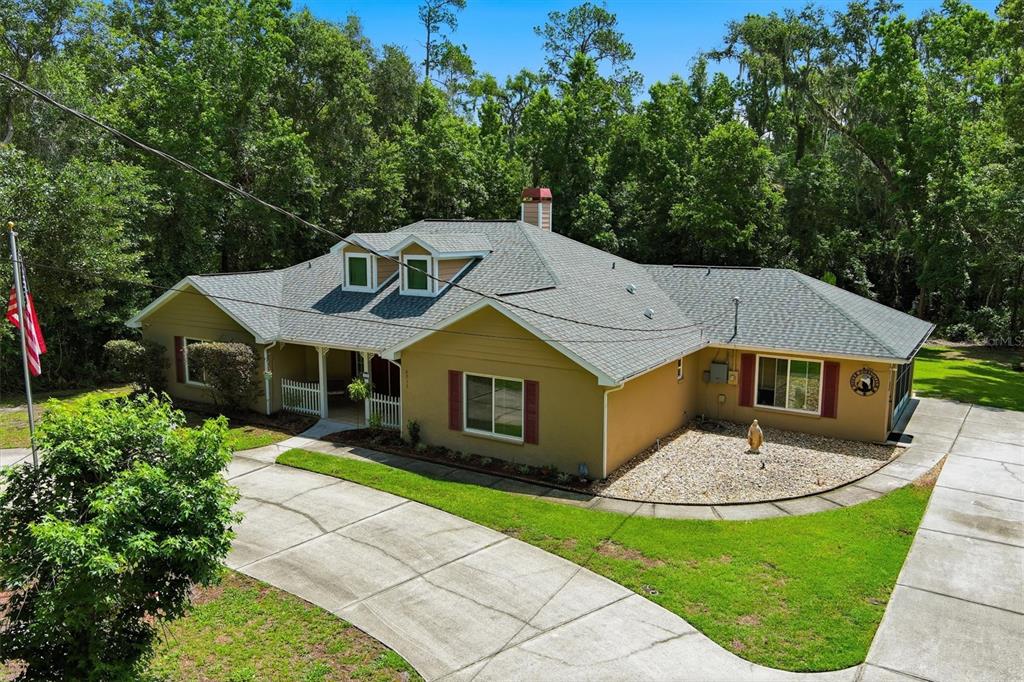 An aerial view of a tan house with red shutters and a gray shingled roof — 6012 VALLEY SPRING DRIVE, BROOKSVILLE, FL