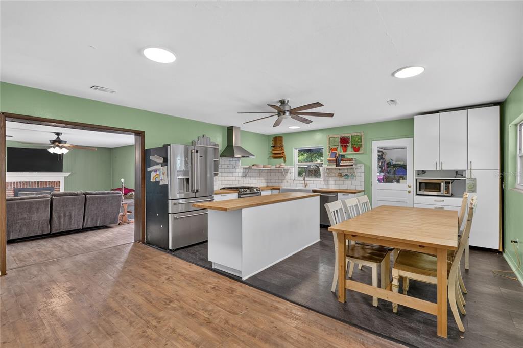 A kitchen with white cabinets, a wooden island, and a dining table on dark flooring — 1805 NE 6TH TERRACE, GAINESVILLE, FL