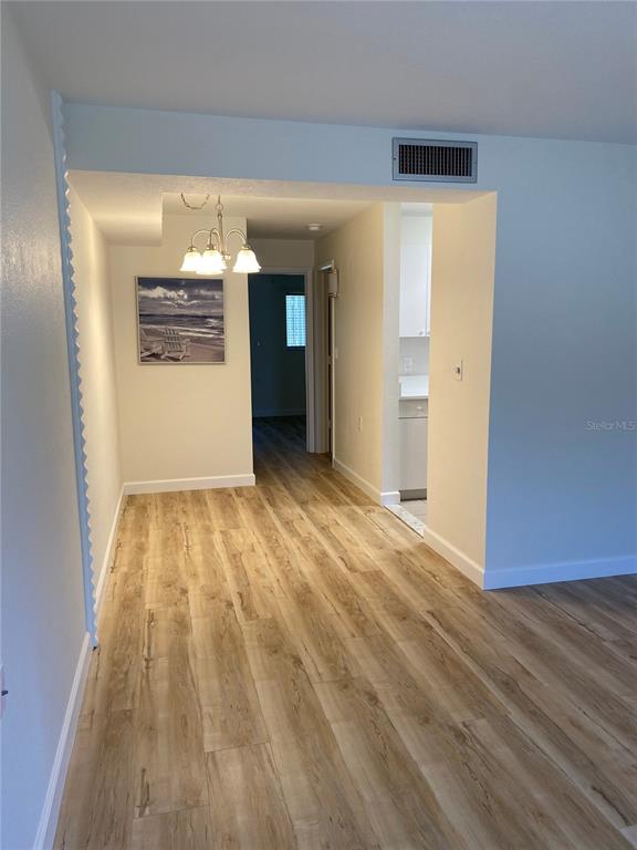 A dining area with wood-look flooring, a chandelier, and a view into a kitchen — 8325 112TH STREET UNIT 106, SEMINOLE, FL