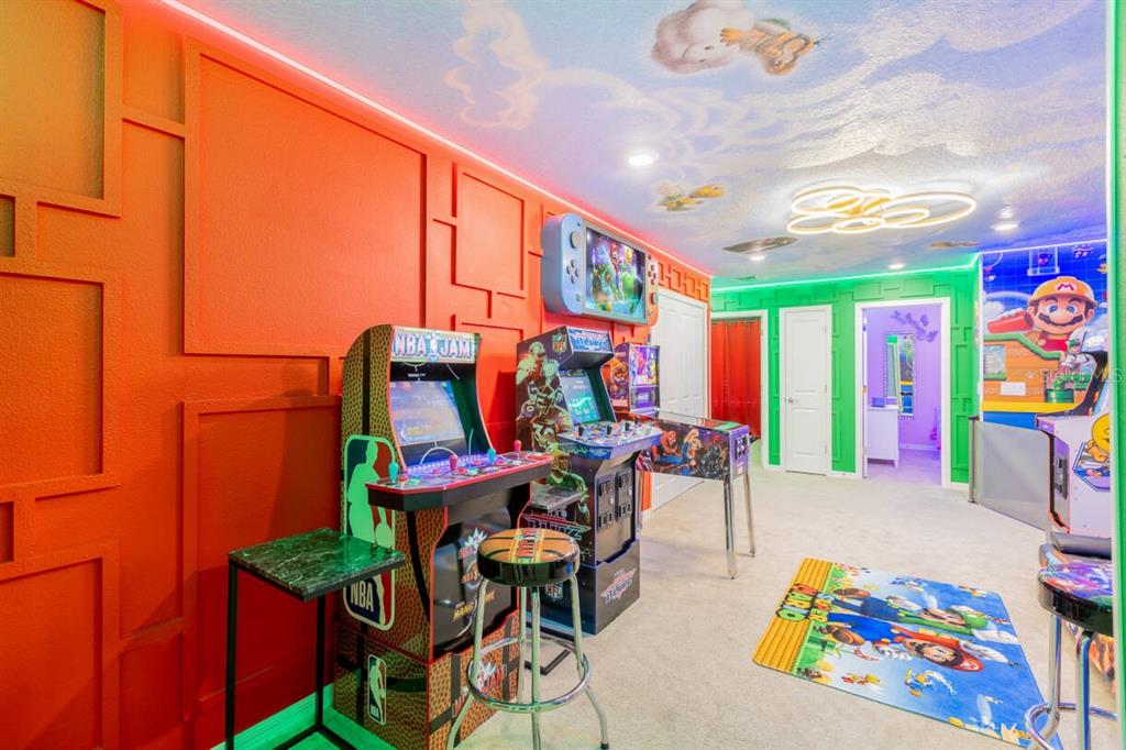 A colorful game room features arcade machines, a pinball machine, and a Mario-themed area rug — 996 PARADISE DRIVE, DAVENPORT, FL
