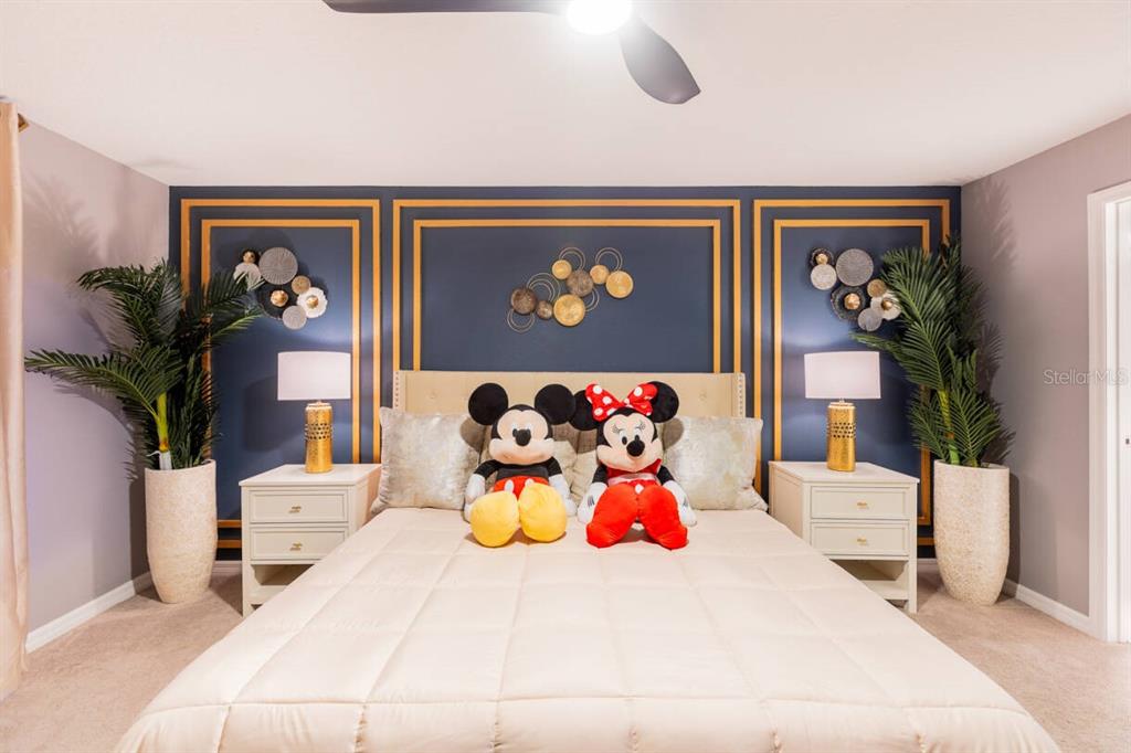 A bedroom features a bed with Mickey and Minnie Mouse plush toys against a navy wall — 996 PARADISE DRIVE, DAVENPORT, FL