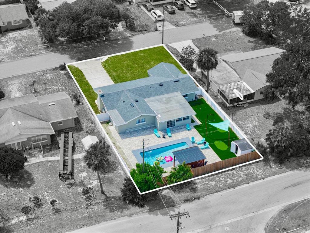 An aerial view shows a house with a backyard pool, patio, and artificial turf lawn — 1818 6TH STREET SE, WINTER HAVEN, FL