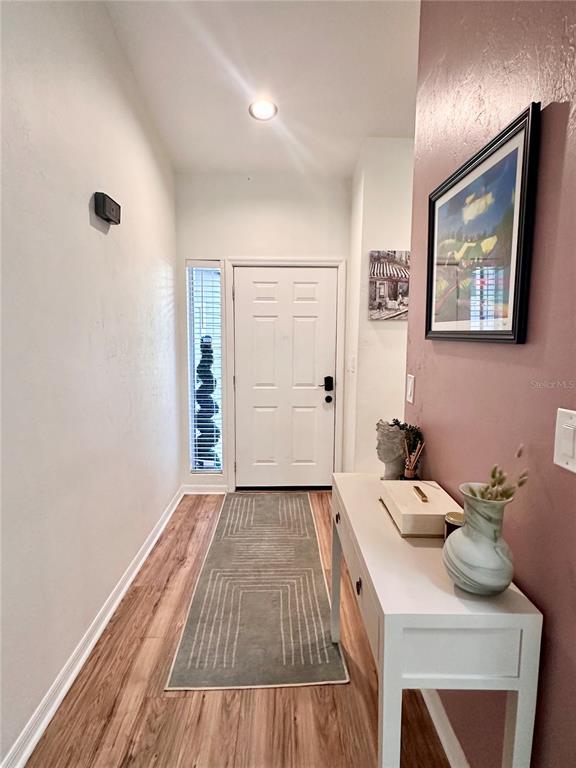 An entryway features wood-look flooring, a white front door with a sidelight, and a console table — 824 NW 124TH DRIVE, NEWBERRY, FL