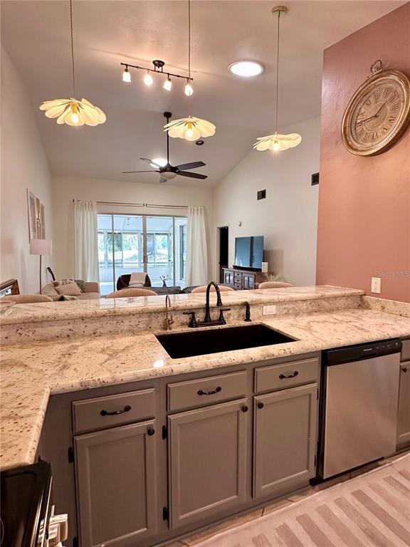 A kitchen with gray cabinets and granite countertops overlooks a living area with a ceiling fan — 824 NW 124TH DRIVE, NEWBERRY, FL