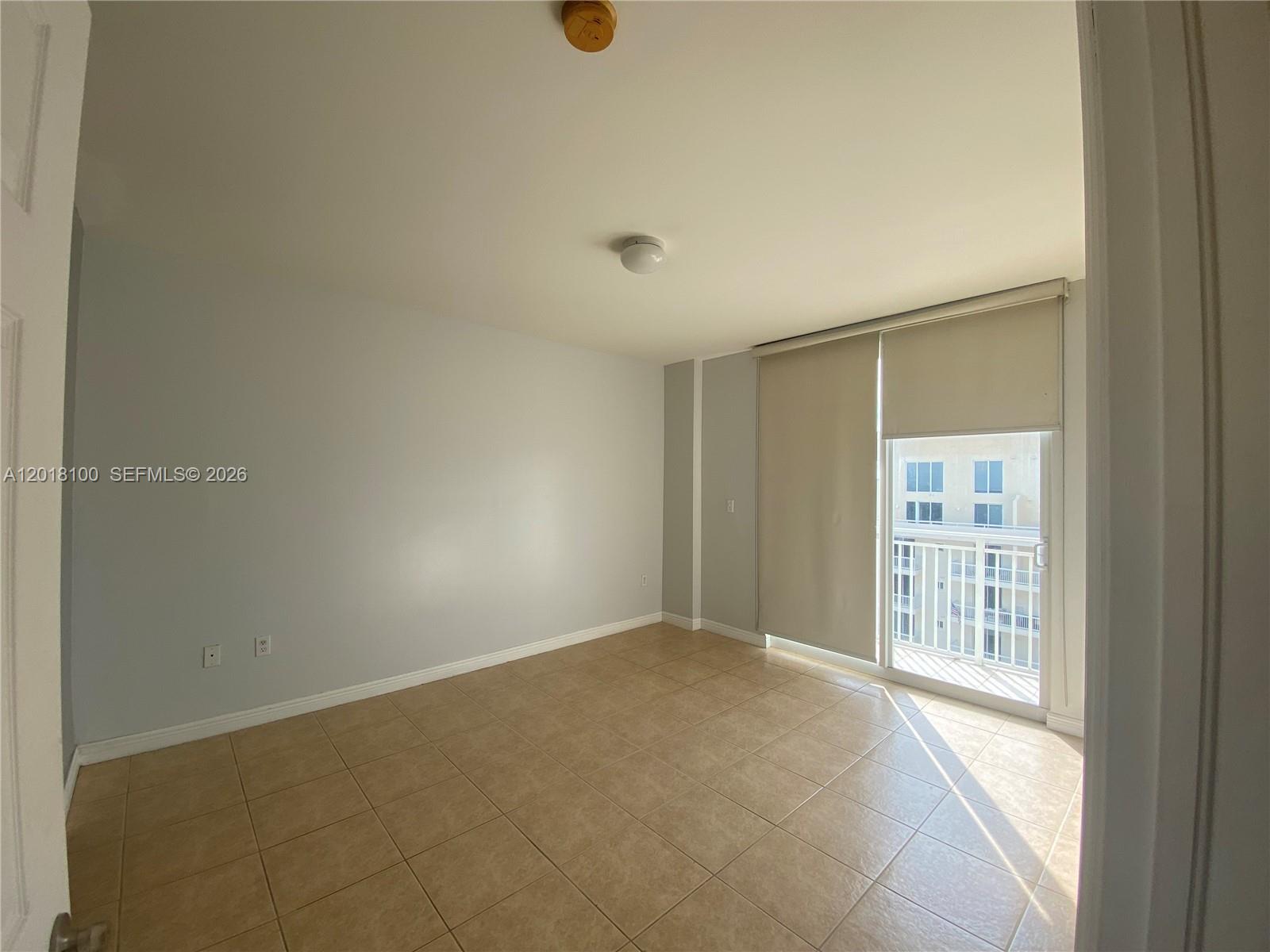 An empty room features light-colored walls, tile flooring, a ceiling light, and a sliding glass door — 2425 SW 27th Ave # 1008, Miami FL 33145, MIAMI, FL