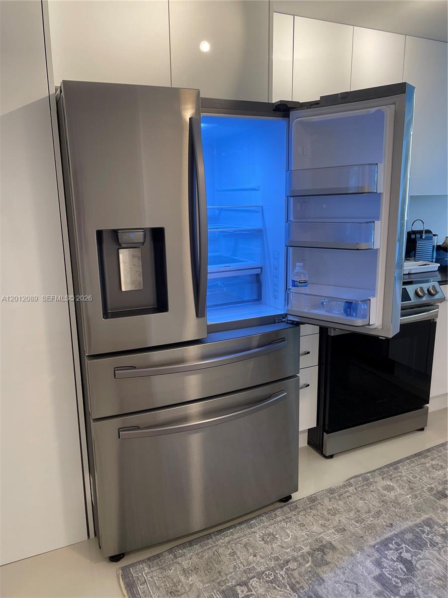 A stainless steel French door refrigerator stands in a modern kitchen with white cabinetry — 10275 Collins Ave # 602, Bal Harbour FL 33154, BAL HARBOUR, FL