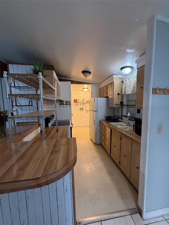 A kitchen with wood-look countertops, light-colored cabinets, a white refrigerator, and a metal shelving unit — 2557 LAKOTA LANE, ST CLOUD, FL