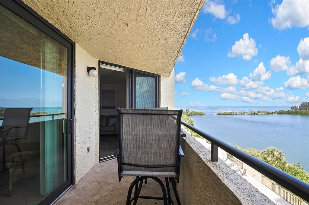 A balcony with a chair overlooks a body of water under a blue sky — 6009 SEA RANCH DRIVE UNIT 414, HUDSON, FL