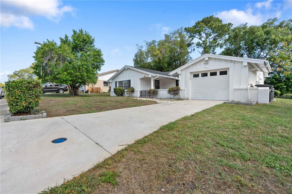 A white single-story house with a garage and a concrete driveway sits on a lawn — 8517 SUNFLOWER LANE, HUDSON, FL