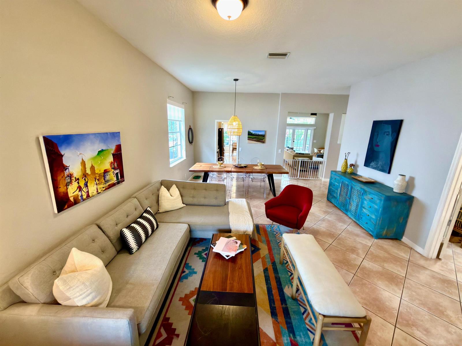 A living room features a grey sectional sofa, a colorful rug, and a blue sideboard — 1618 Royal Grove Way, Weston FL 33327, WESTON, FL