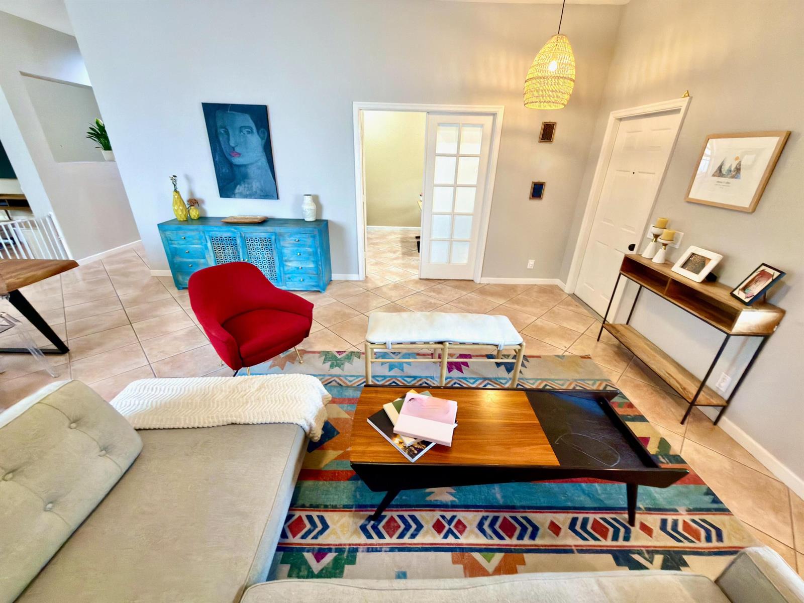 A living room features a colorful patterned rug, a red armchair, and a wooden coffee table — 1618 Royal Grove Way, Weston FL 33327, WESTON, FL