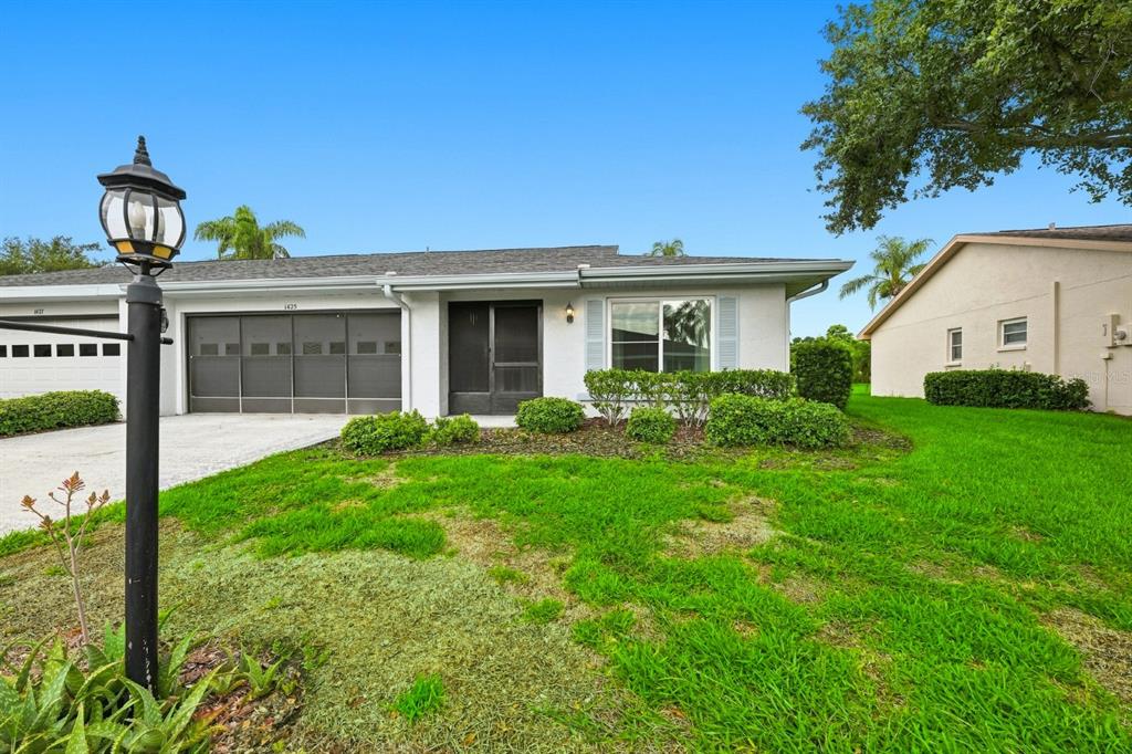 A single-story house with a white exterior, a garage, and a front lawn — 1425 LELAND DRIVE, SUN CITY CENTER, FL
